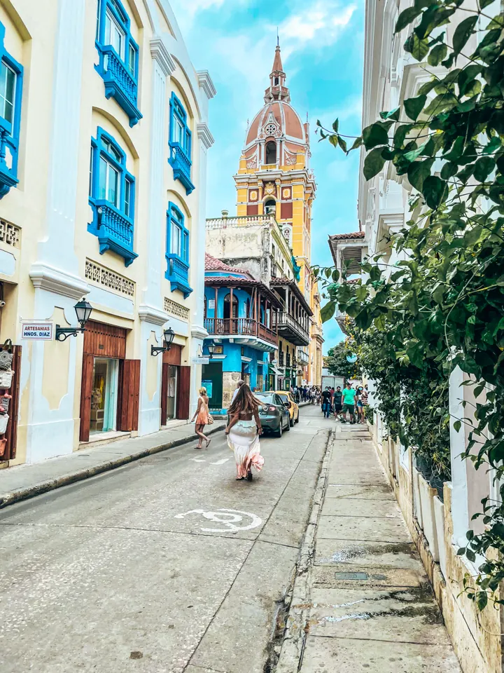 A colorful colonial street in Cartagena's old city leading to a church dome