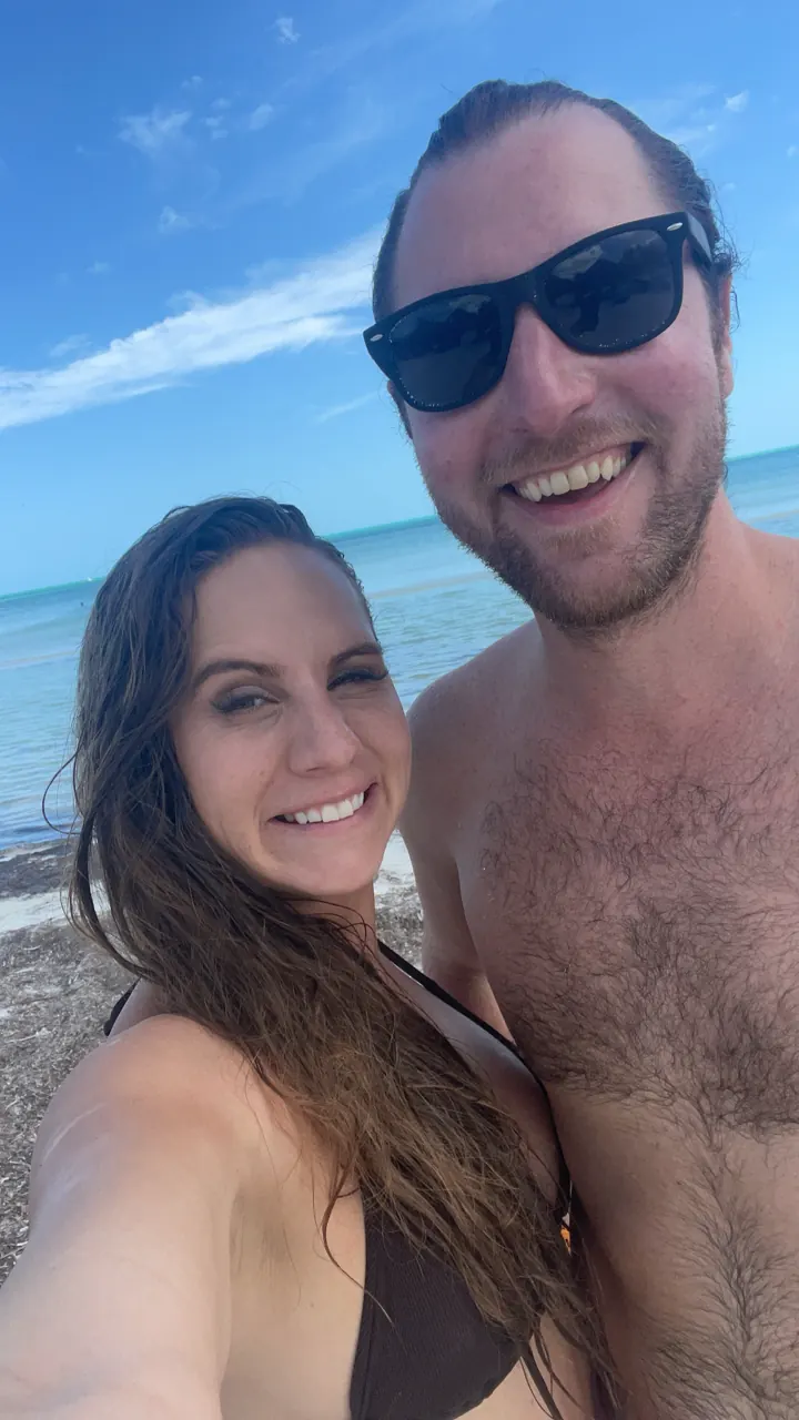 A couple taking a selfie on a white-sand beach on Holbox